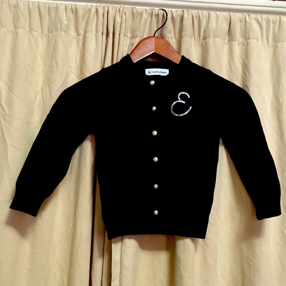 Girl’s black cardigan sweater with “E” initial. Size 5/6.